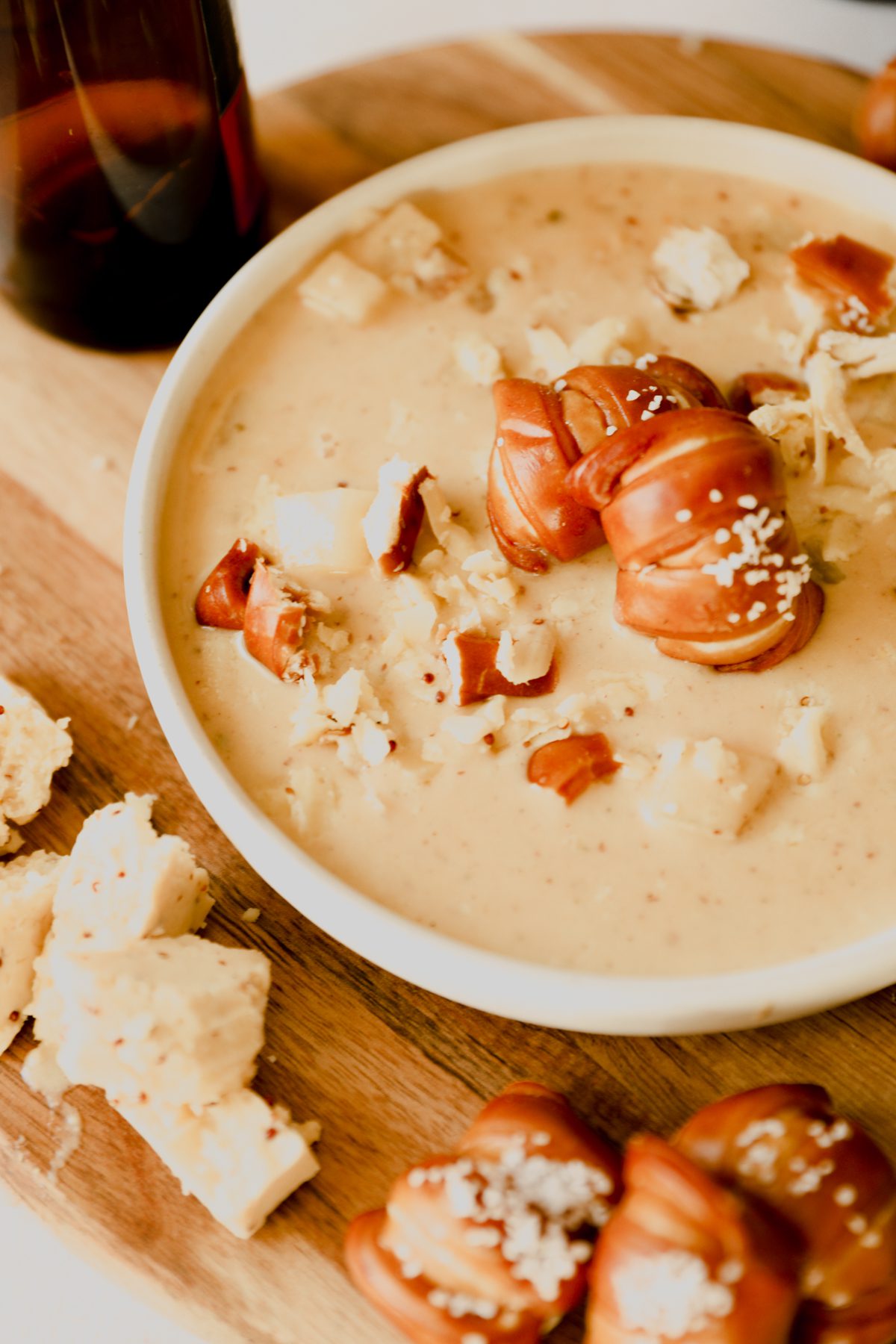 close up shot of a bowl of beer cheese soup with pretzel topping 
