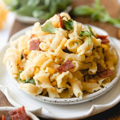 white plate piled high with chicken, bacon, sweet corn pasta