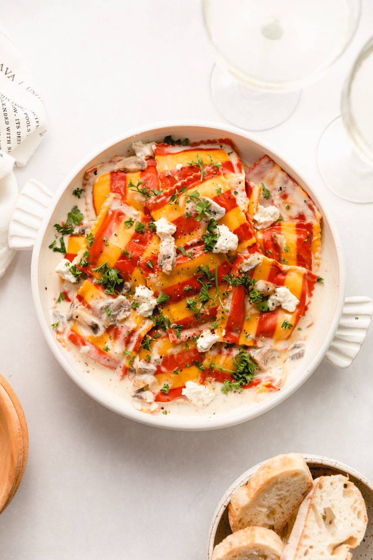 bowl of lobster ravioli with mushroom cheese wine sauce garnished with parsley. 
