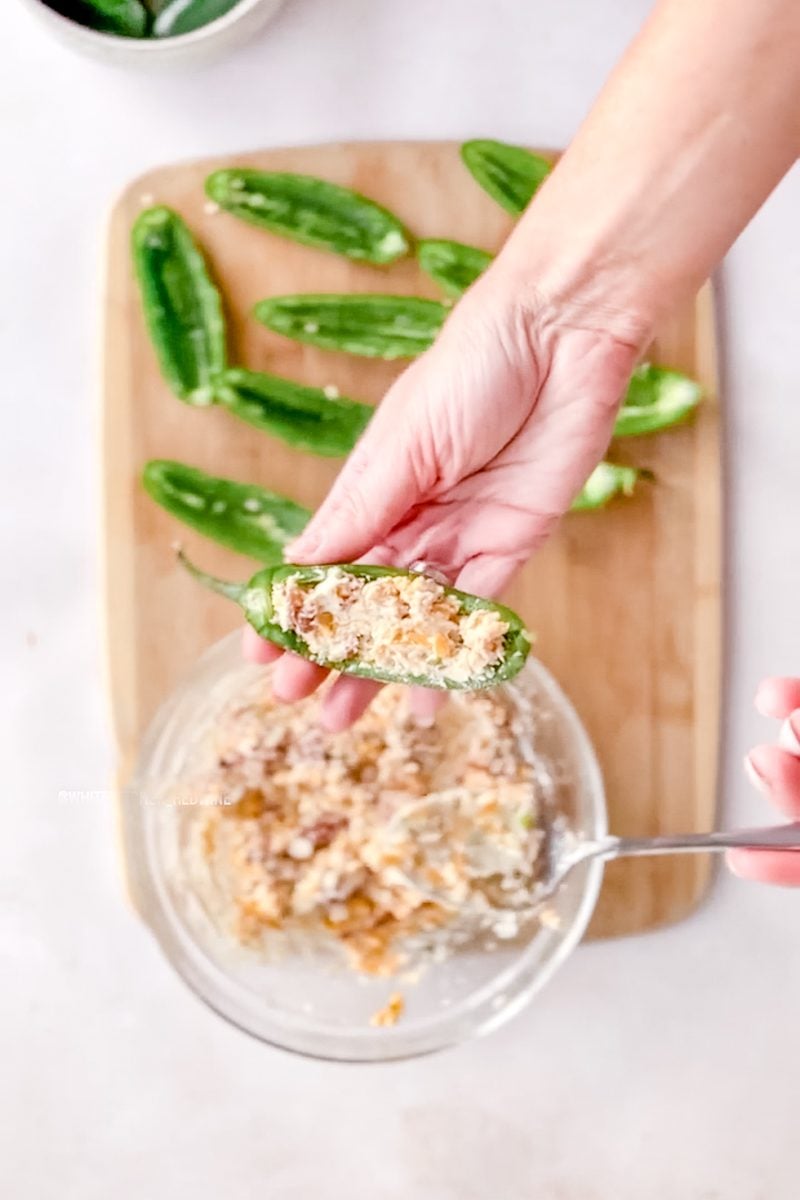 filling the jalapeno poppers with cream cheese and bacon filling