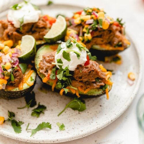 white plate with stuffed avocados topped with sour cream