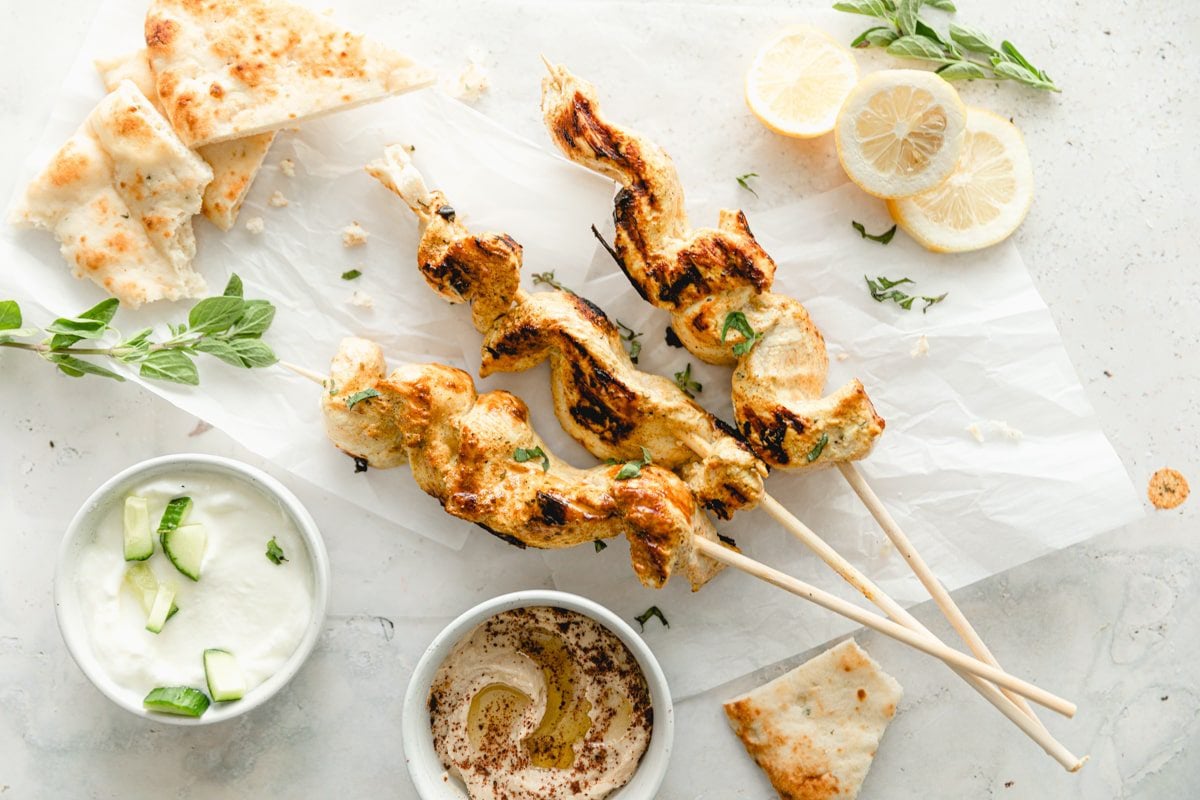 3 greek yogurt chicken kebabs on parchment paper
