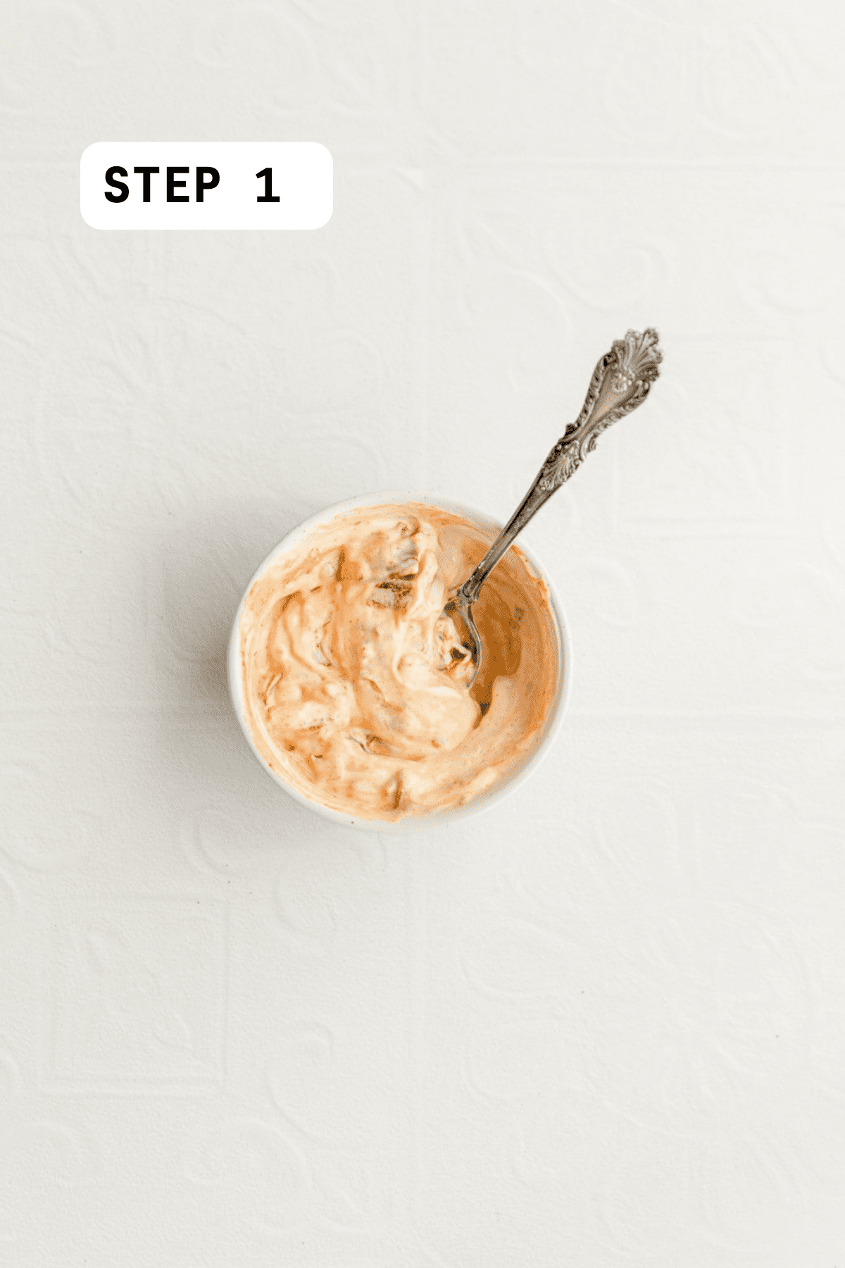 Chipotle peppers mixed with mayo with a spoon in the bowl. 