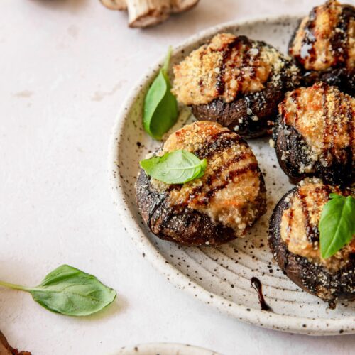 plate of stuffed mushrooms topped with fresh basil leaves