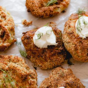 multiple air fried potato fritters topped with sour cream dollop and chives