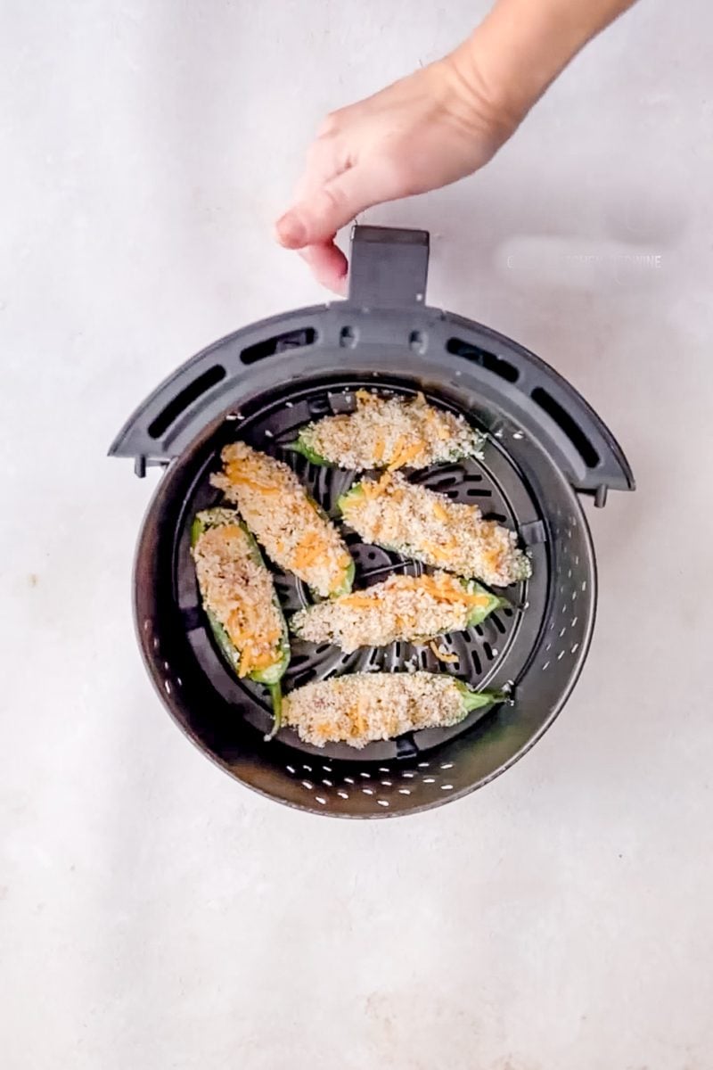 air fryer basket with a few jalapeno poppers in it
