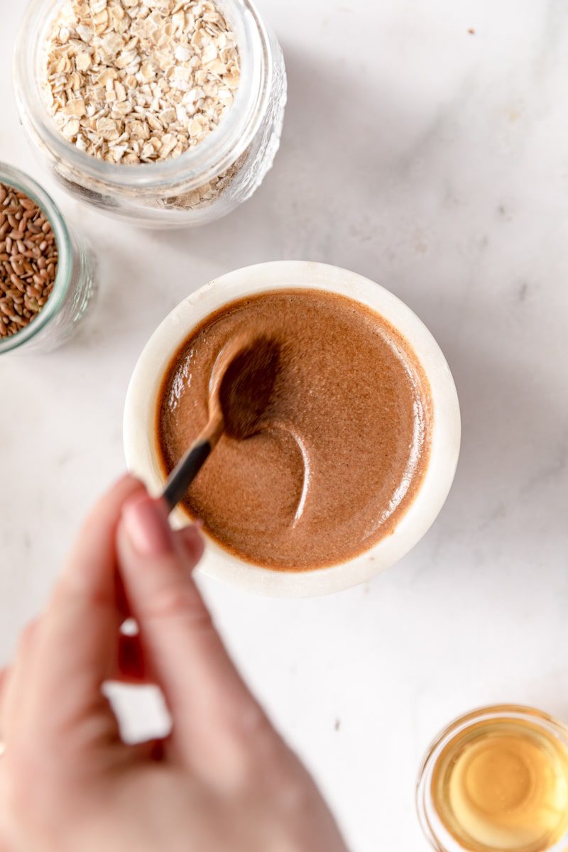 a spoon stirring granola butter in a white bowl