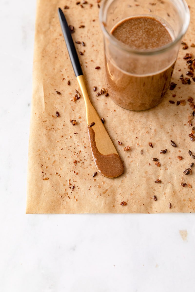 small knife with granola butter on it laying on a piece of parchment