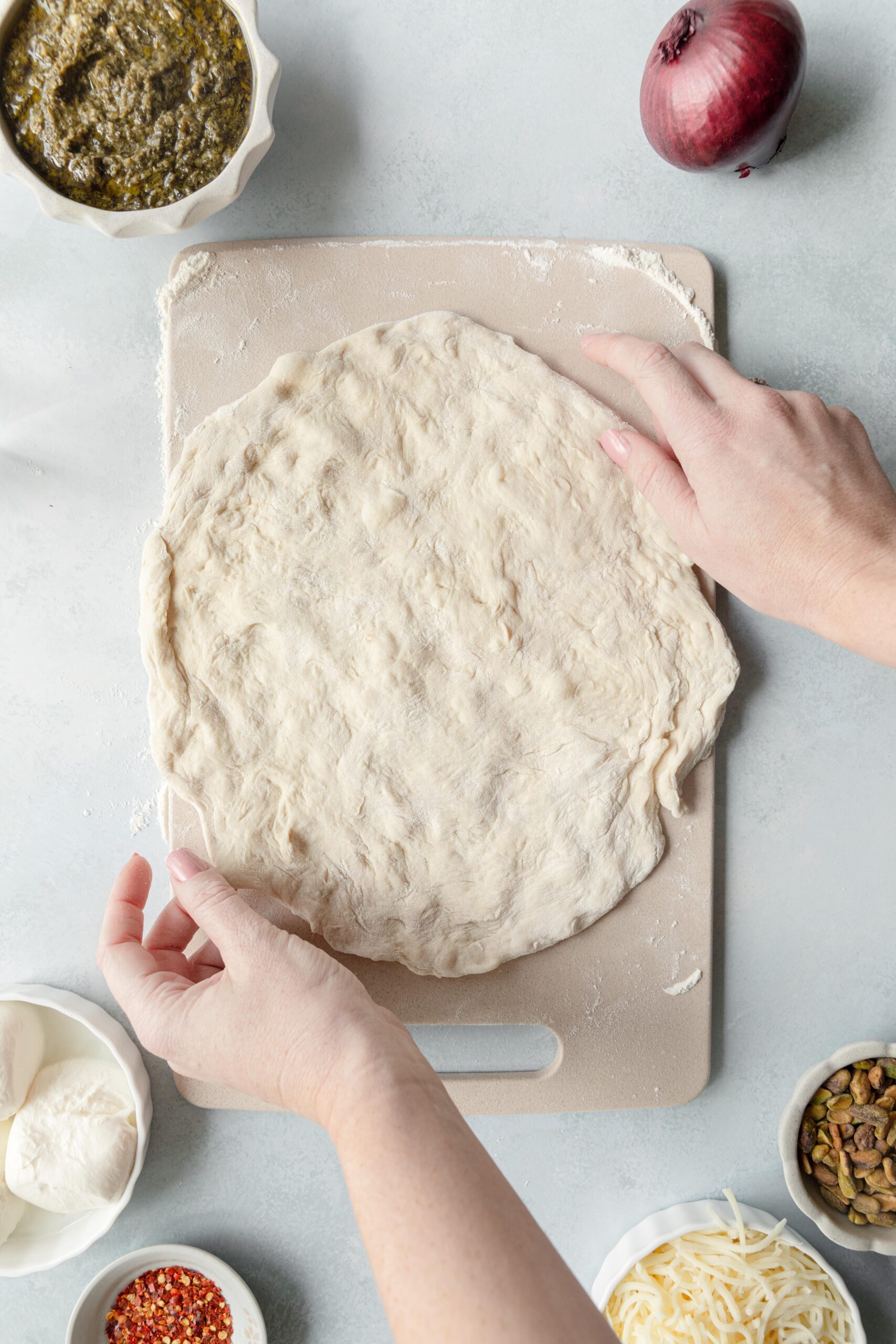 rolling out pizza dough on a cutting board