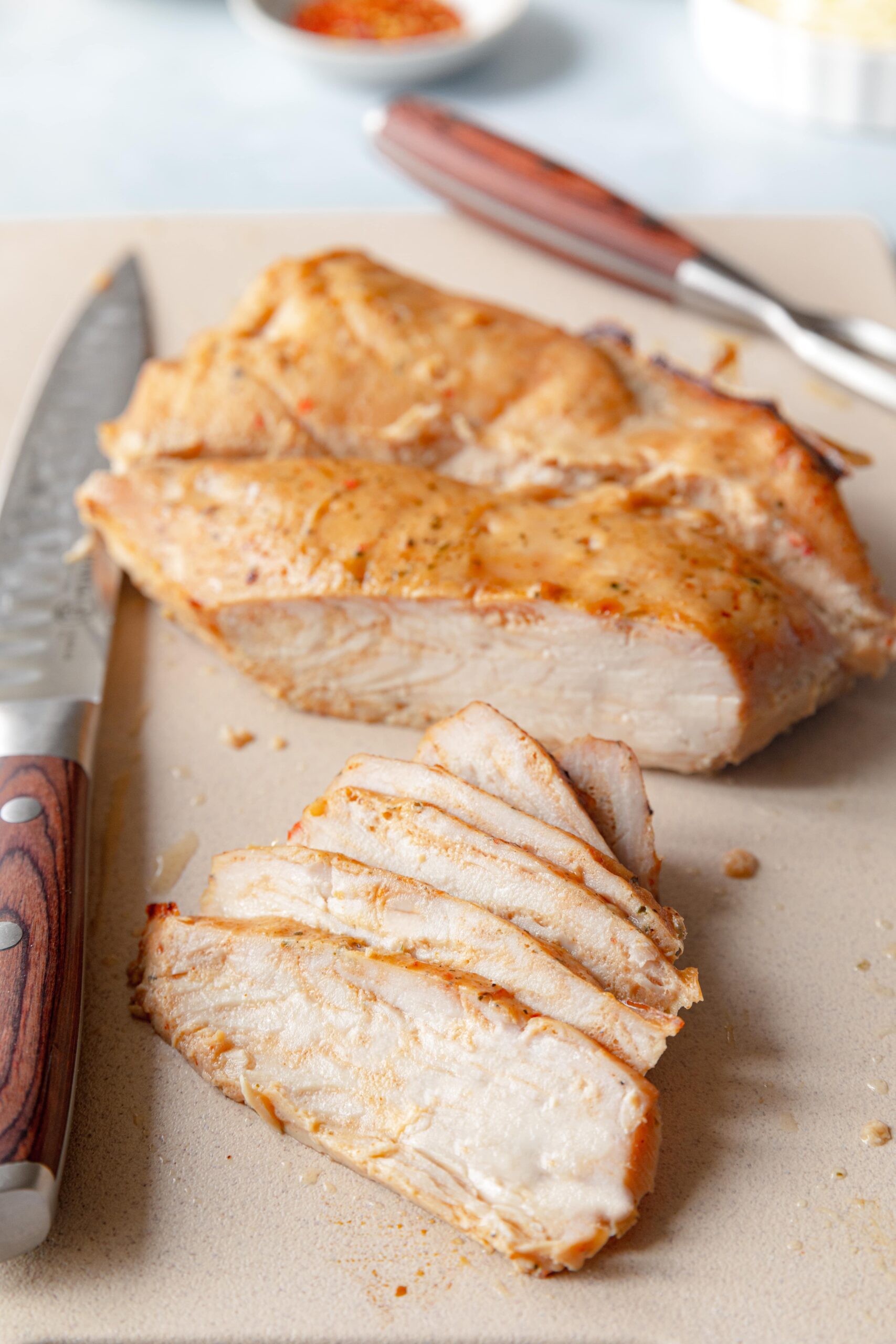 sliced turkey tenderloin on a cutting board with a knife beside it