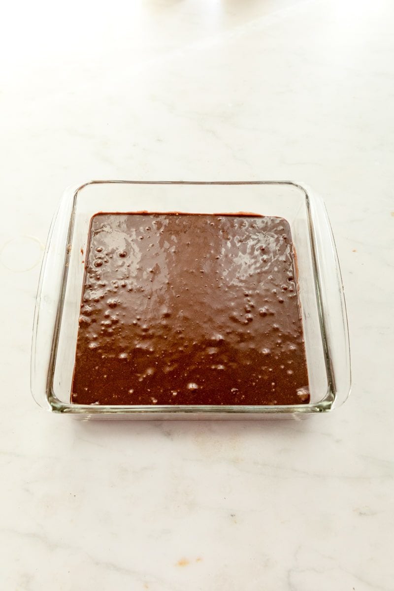 glass baking dish with brownie mix poured in