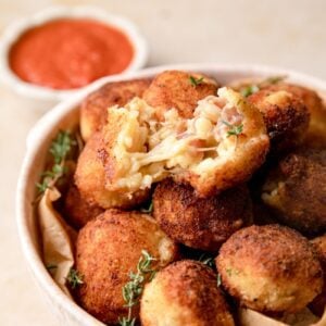 close up photo of arancini ball cut in half with a cheese pull