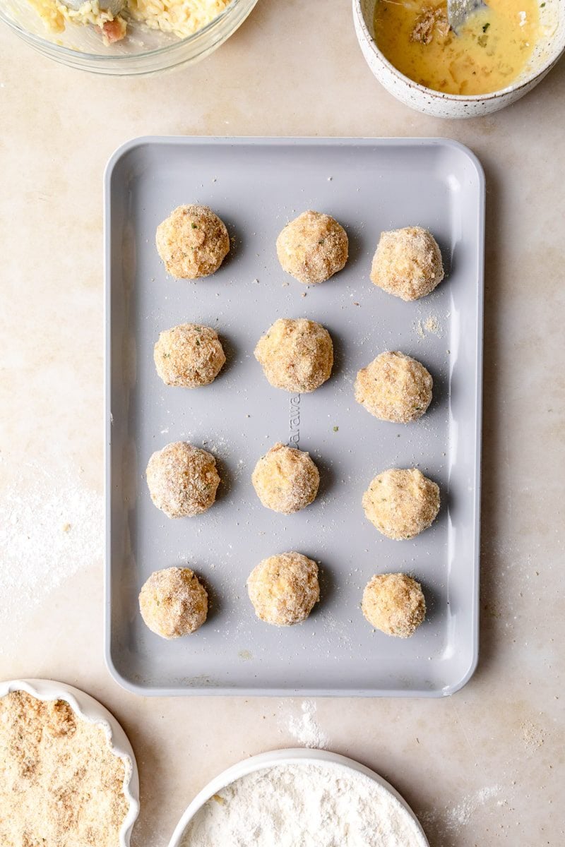 balls of arancini on a sheet tray before frying