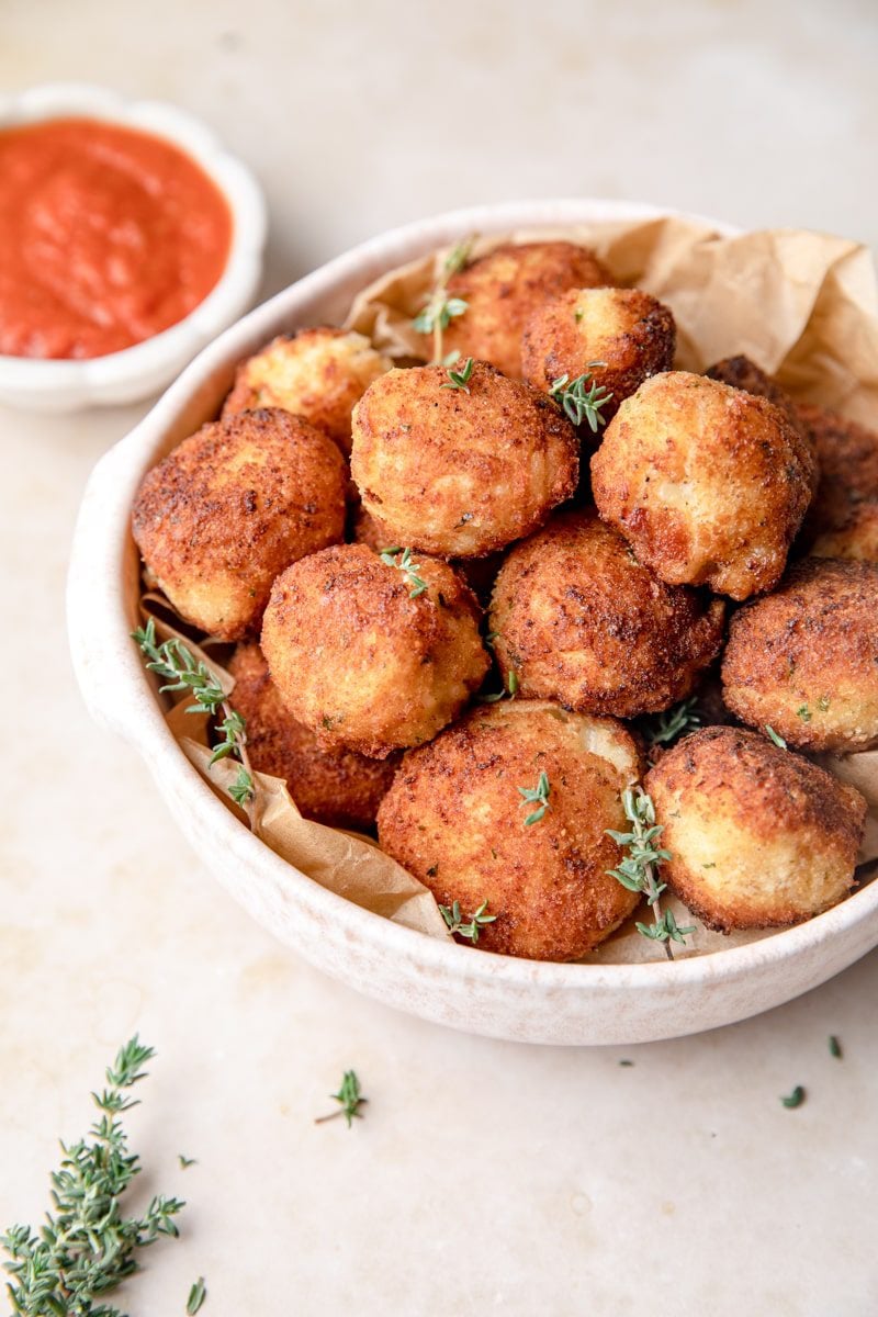 a bowl of arancini with thyme leaves as garnish