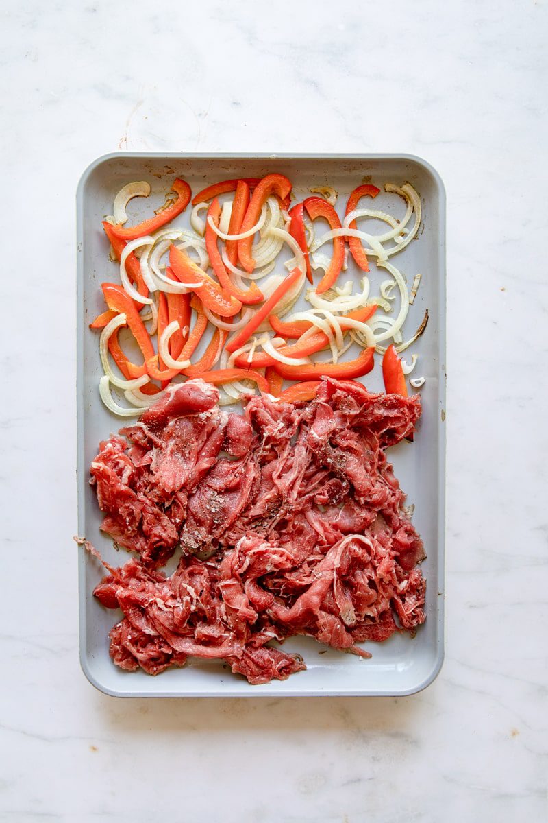 close up overhead photo of the sheet tray with shaved beef added to it