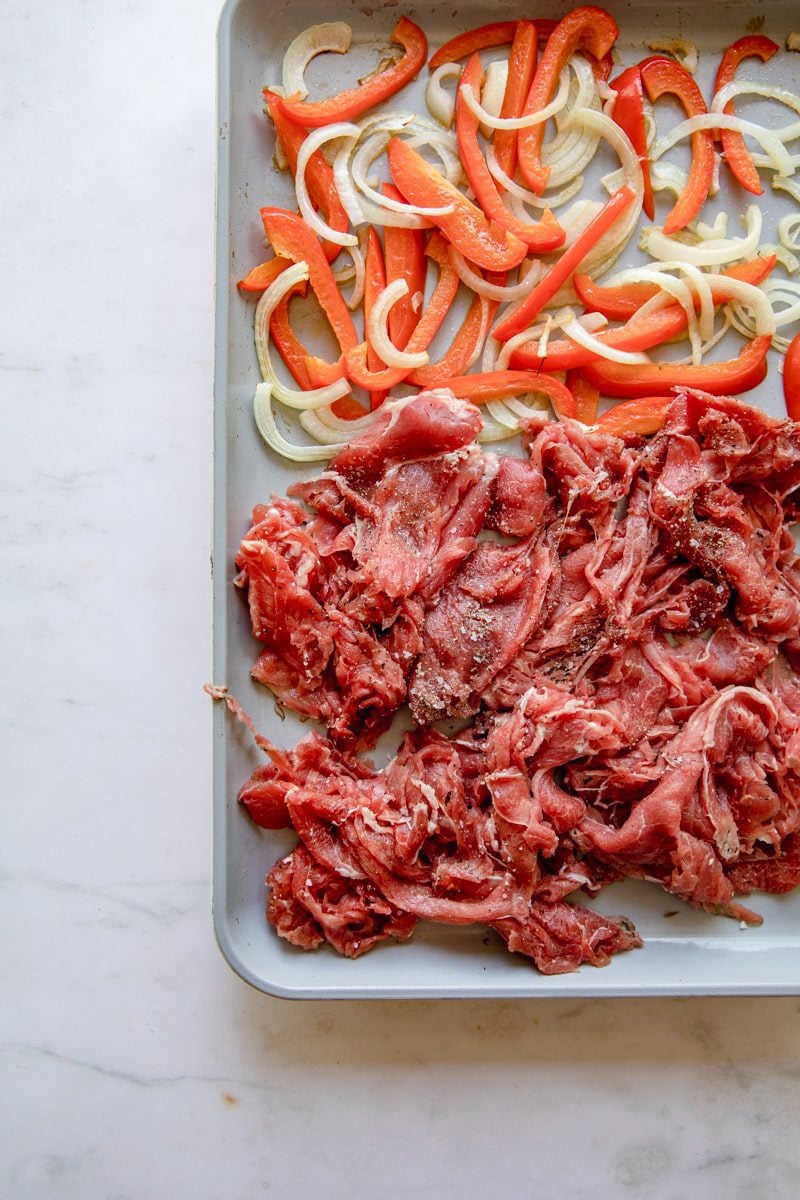 close up overhead photo of the sheet tray with shaved beef added to it