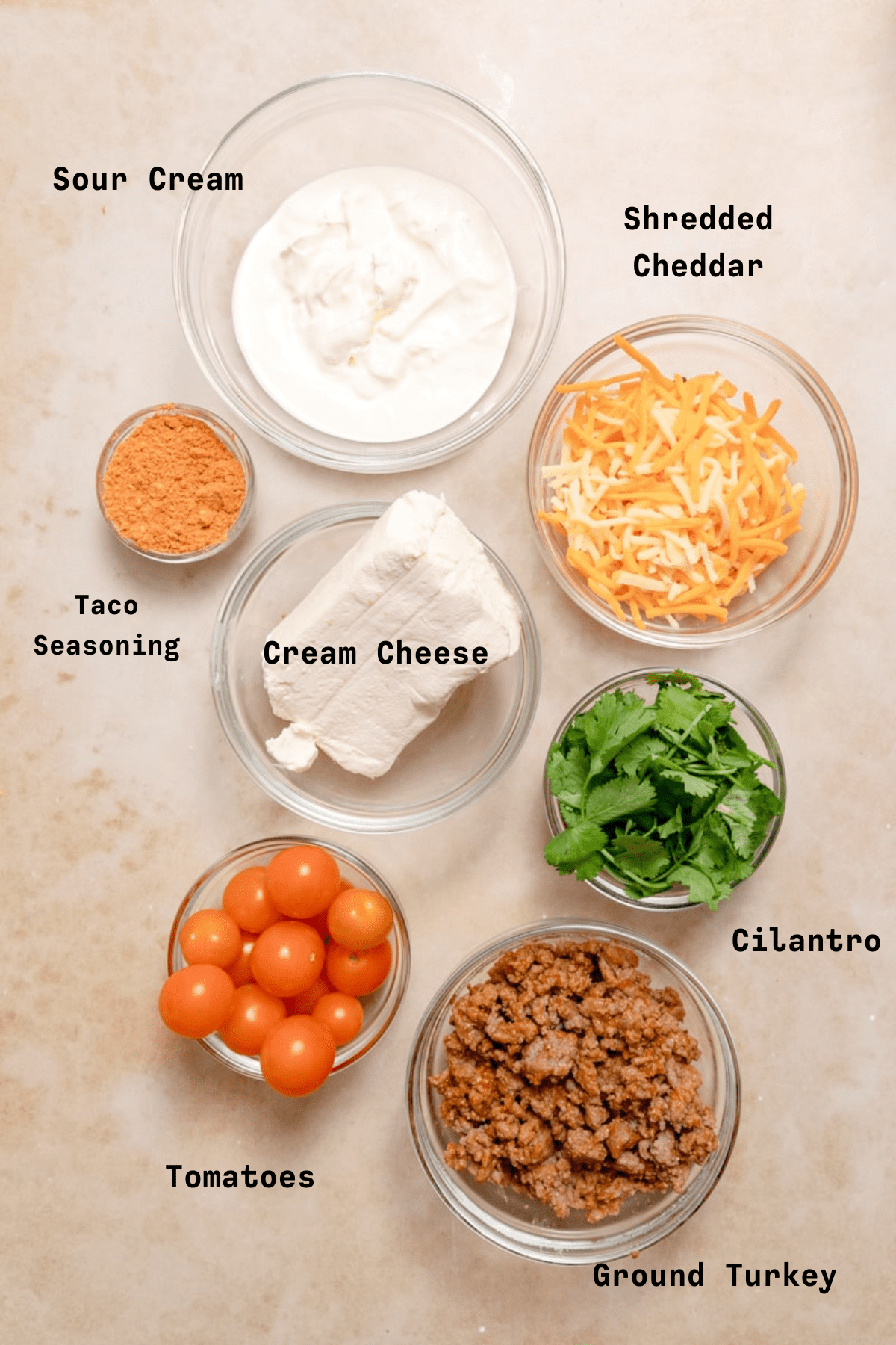 overhead photo of taco dip ingredients in glass bowls