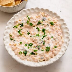 mexican corn dip in a white bowl with tortilla chips on the side