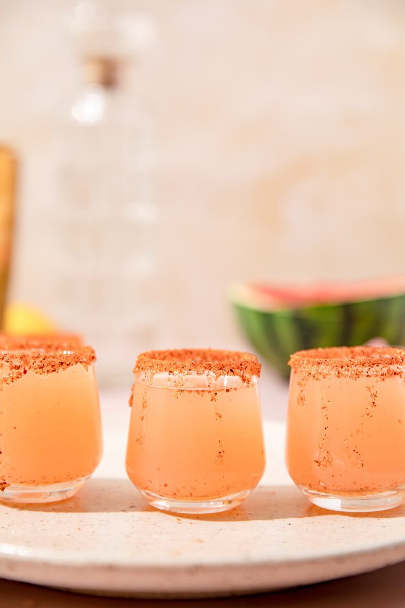 vertical photo of 3 Mexican candy shots lined up with a tajin rim