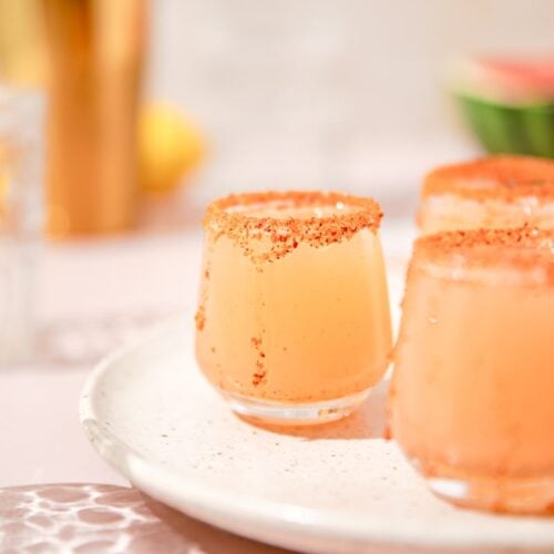 white plate with Mexican candy shots rimmed with tajin seasoning