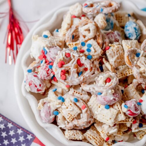white bowl of patriotic party mix with American flags surrounding