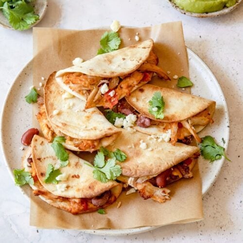 overhead photo of mini rotisserie chicken tacos on a plate with parchment paper