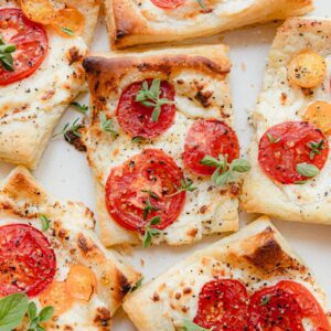 puff pastry tarts with cheese and tomatoes on a white plate