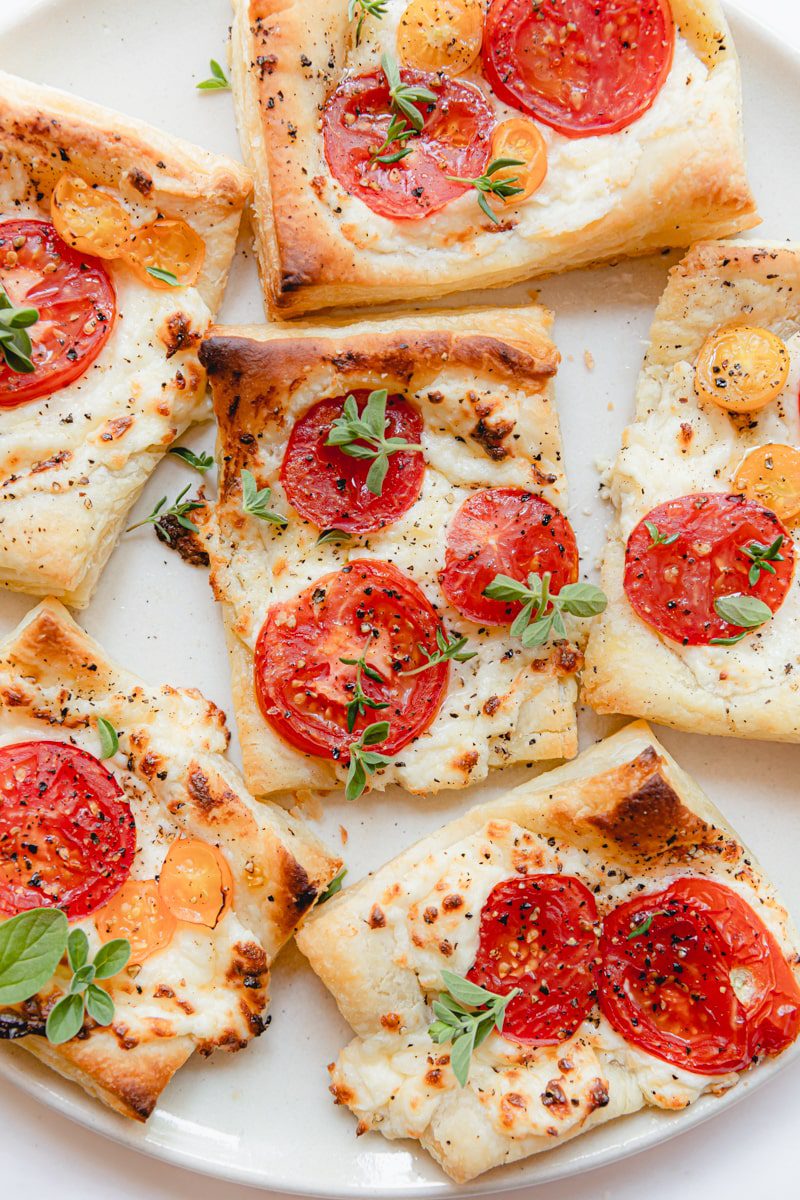 puff pastry tarts with cheese and tomatoes on a white plate