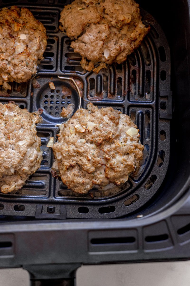 cooked turkey burgers in an air fryer basket 