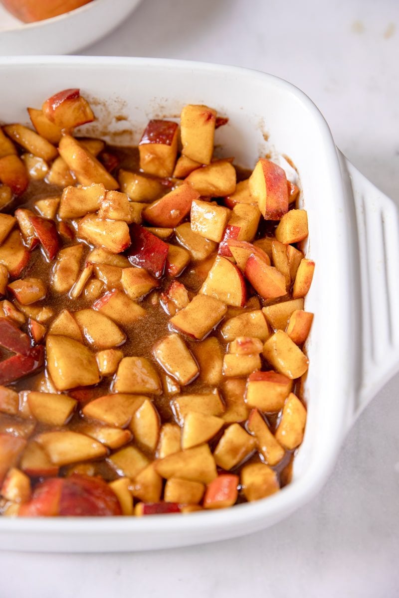 Peach cobbler filling in a white baking dish