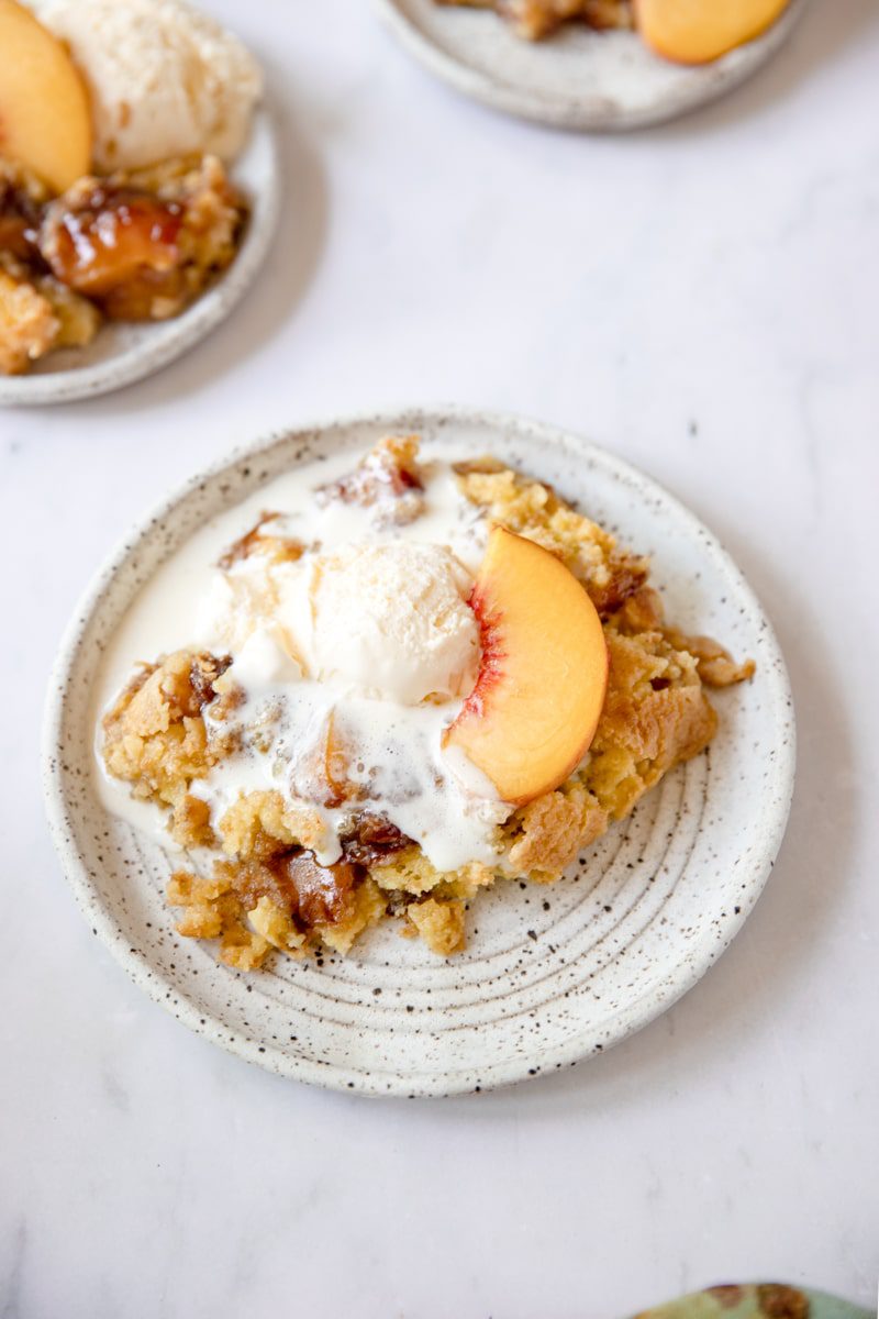 plated peach cobbler with cake mix and ice cream on top