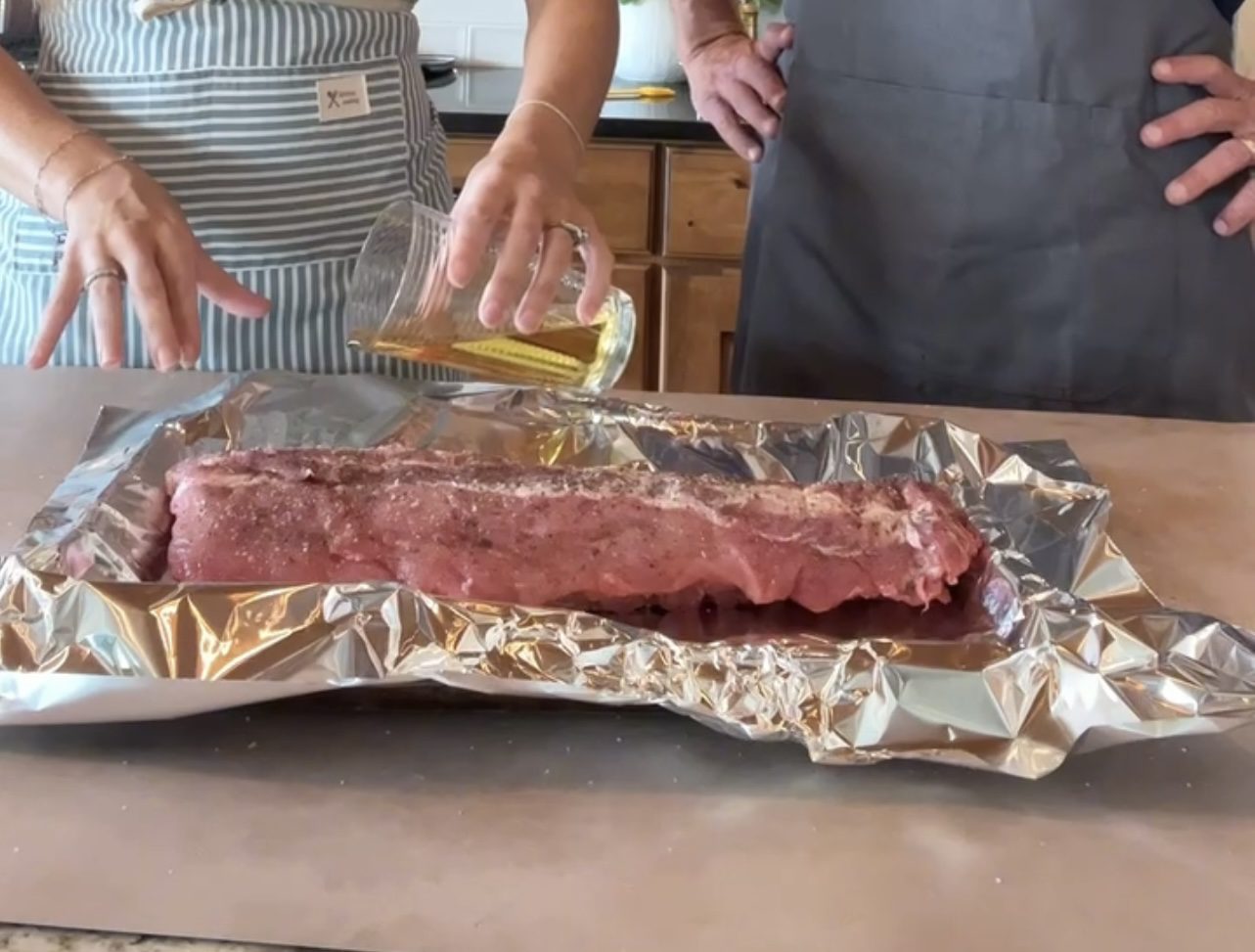 pouring apple juice over rack of ribs