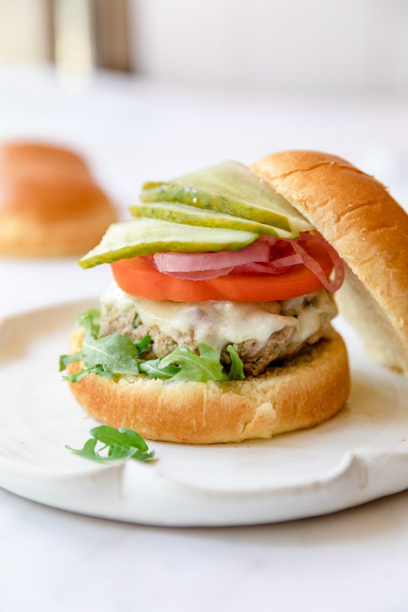 air fryer turkey burger layered with toppings and the top bun off to the side 