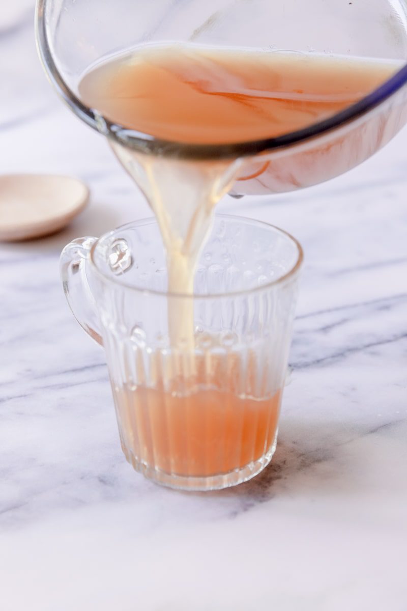 pouring the warm medicine ball tea into a clear glass mug