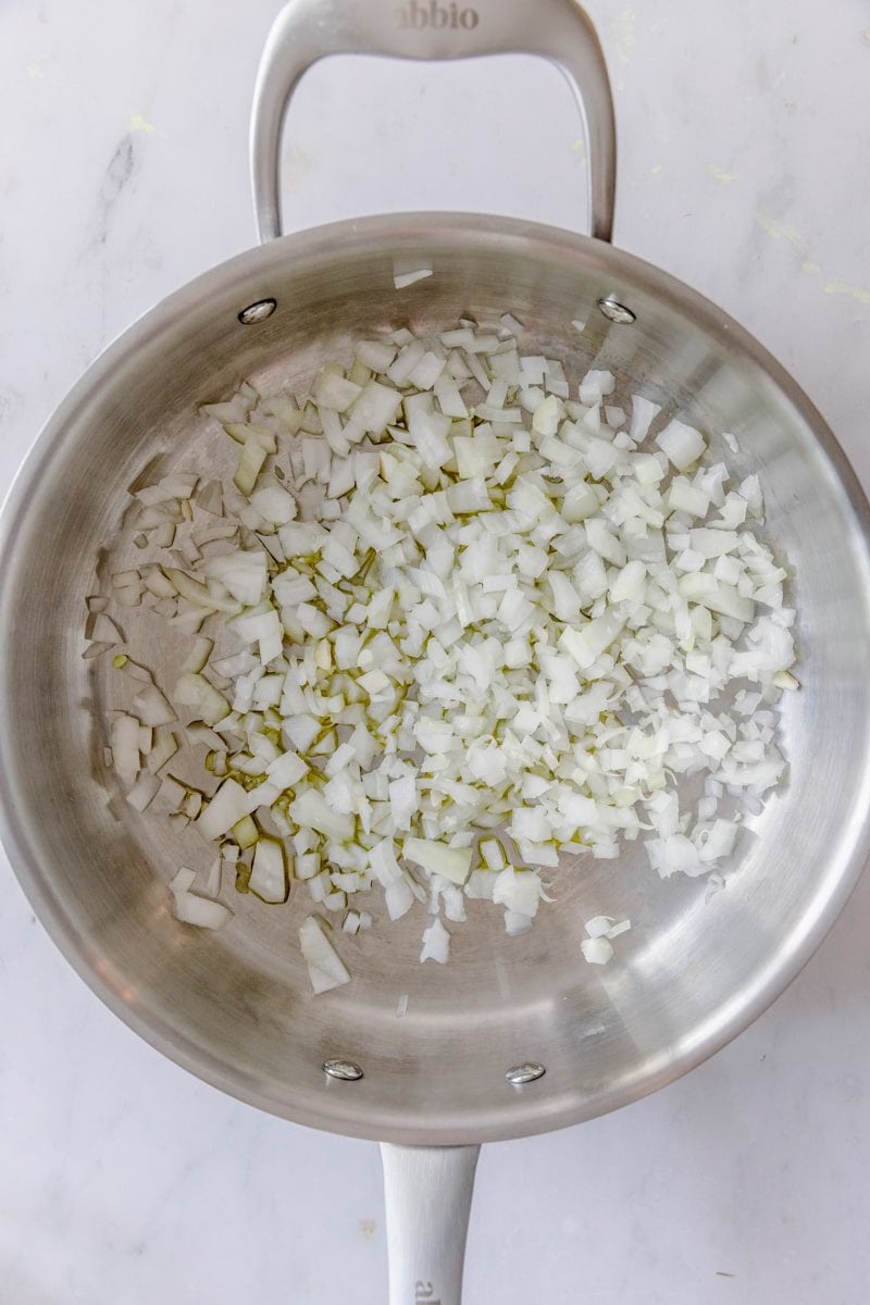 overhead photo of sautéing onions in a skillet with olive oil