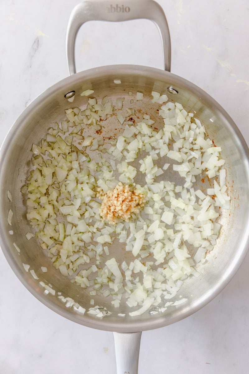 overhead photo of garlic and onions sautéing in a pan