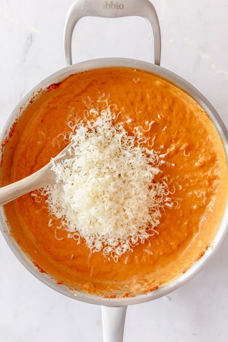 stirring parmesan cheese into the skillet with pumpkin and veggies 