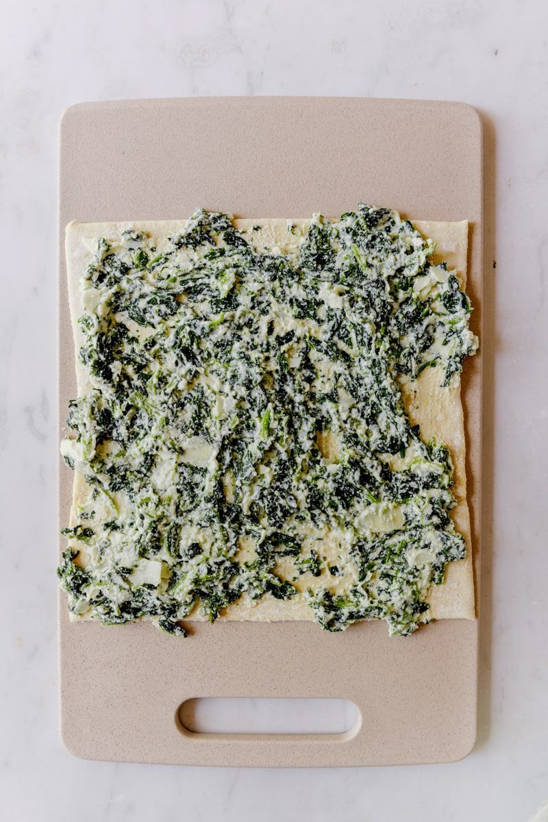 Spinach ricotta filling spread out on a sheet of puff pastry