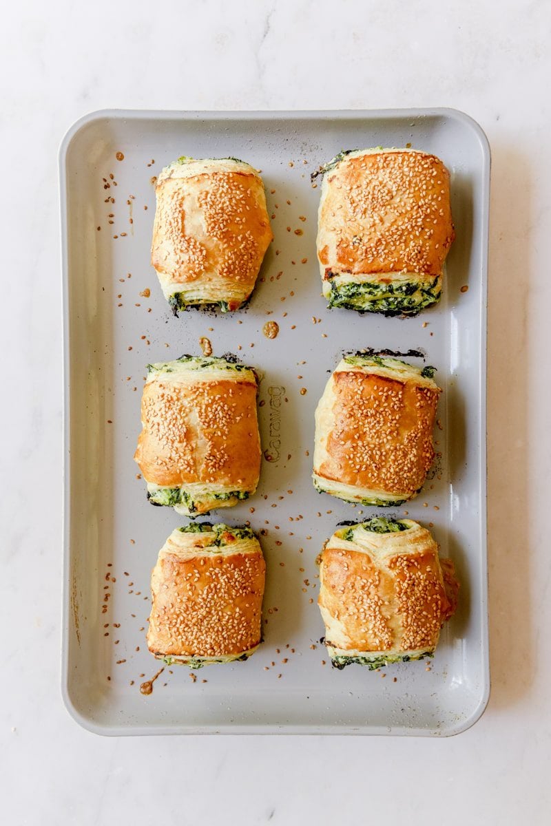 6 baked puff pastry spinach and ricotta roll ups on a baking sheet