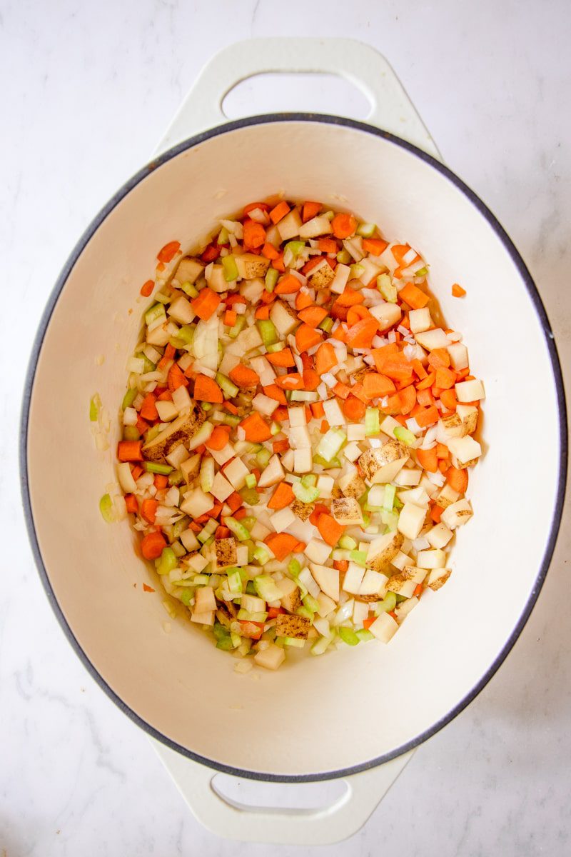 sautéed veggies in a large white dutch oven 