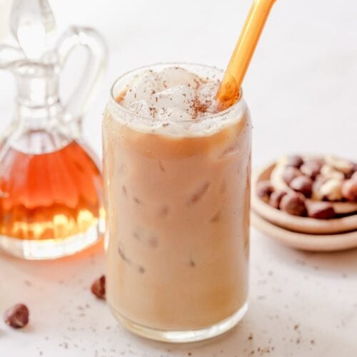 iced hazelnut latte mixed up in a glass with an orange straw