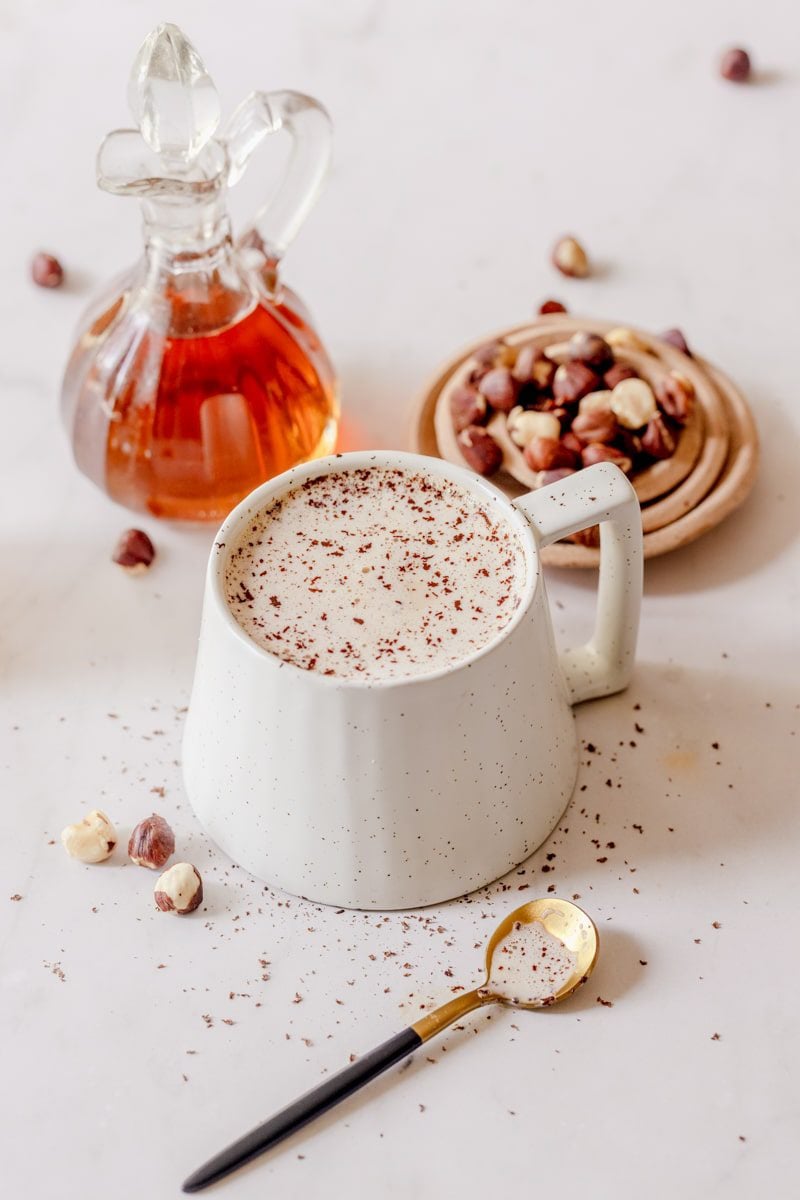 hot hazelnut latte in a white mug with chocolate shavings on top