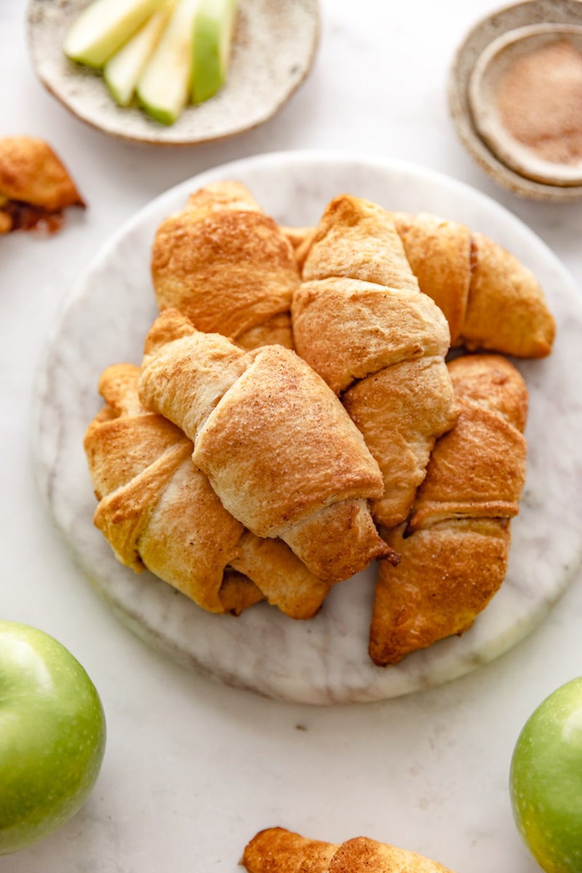 Marble plate stacked with baked apple crescent rolls.