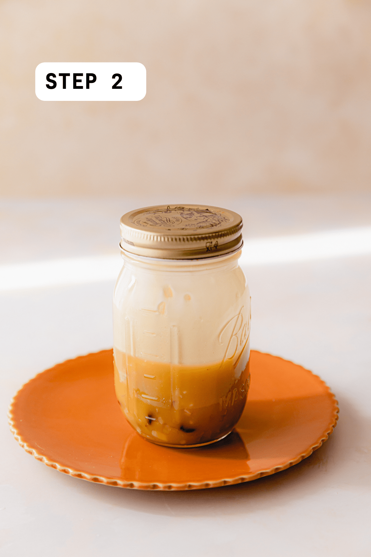 Maple Cranberry Vinaigrette dressing shaken up and combined in a mason jar sitting on an orange plate.