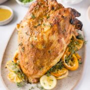 Bone in breast turkey plated with fresh lemon slices and sprigs of thyme.