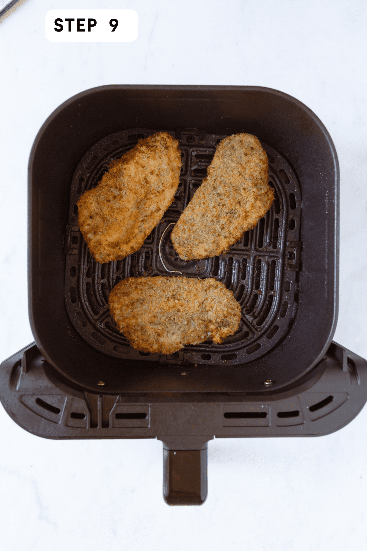 3 cooked chicken cutlets in an air fryer basket. 