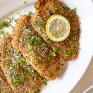 Plate of air fried chicken cutlets garnished with a lemon.