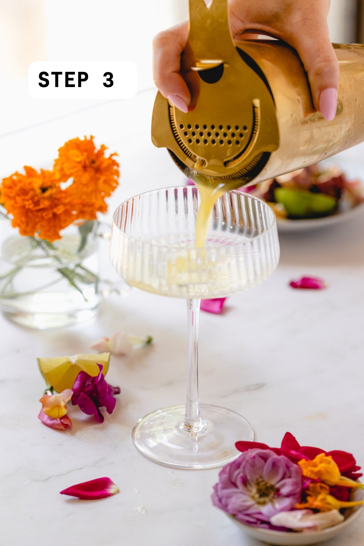 Straining passion fruit cocktail into a coupe glass. 