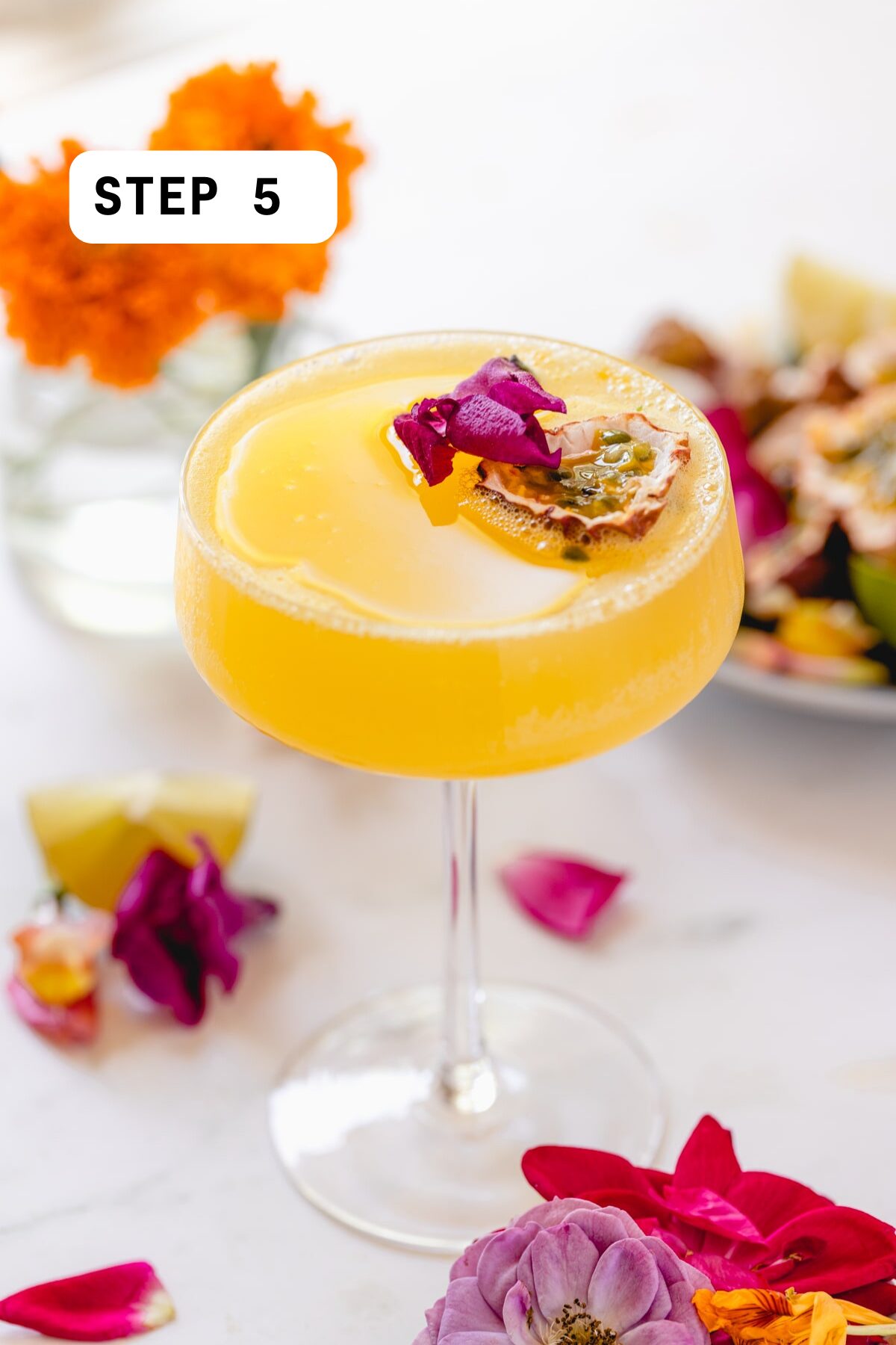 A passion fruit martini with half a passion fruit and edible flowers as garnish. 