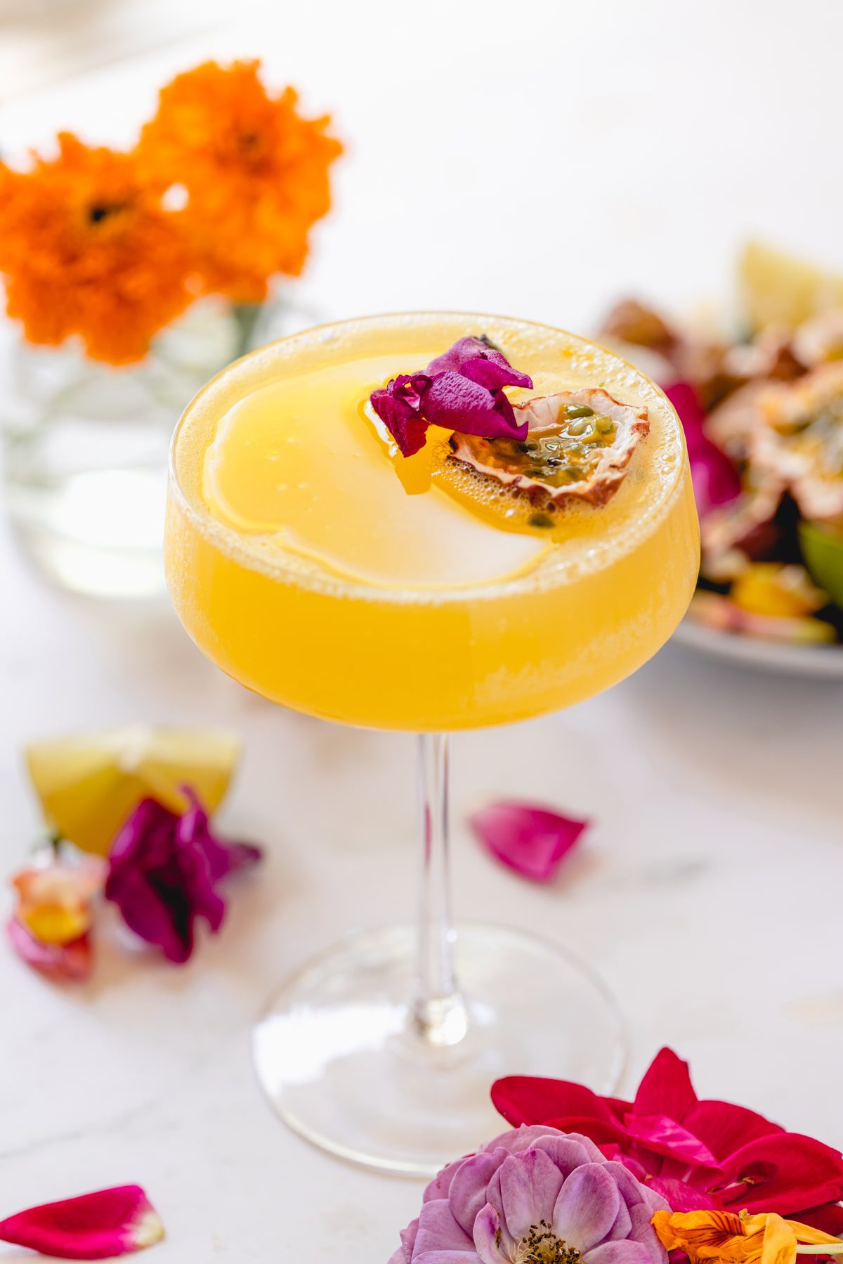 Passion fruit martini in a coupe glass garnished with edible flowers. 